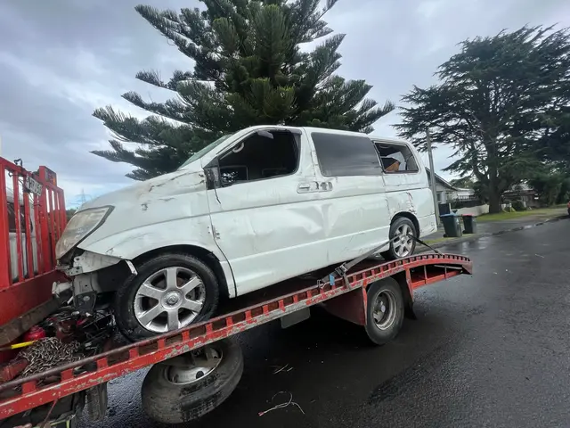 Damaged white van loaded on a tow truck in a North Shore street